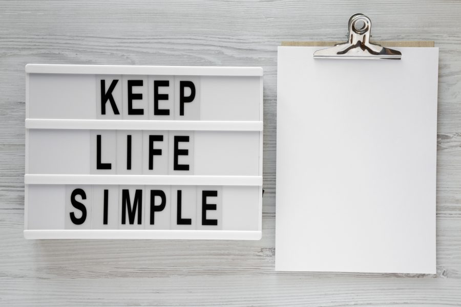 A sign next to a clip board. The sign says: keep Life Simple