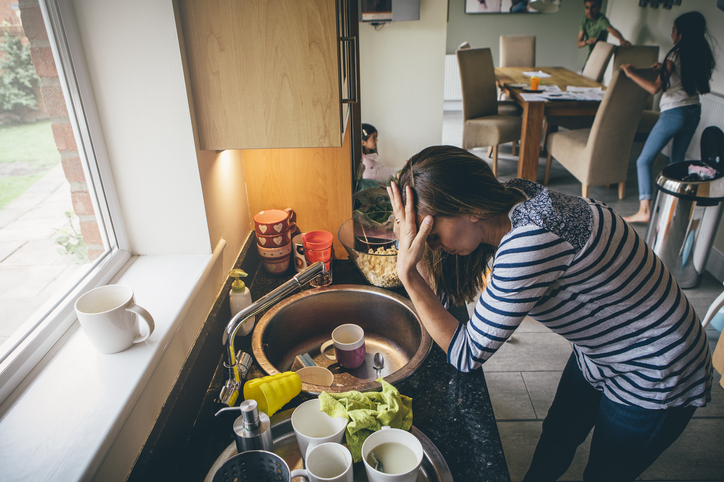 a woman, overwhelmed, at a sink full of dishes who wants to learn how to organize your life