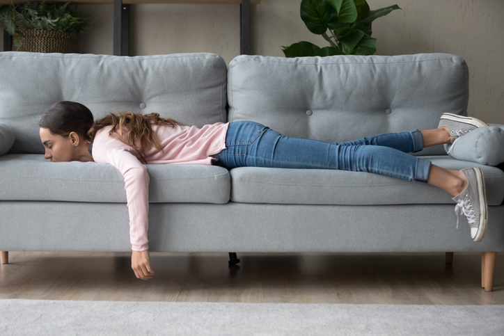 Girl lying on a couch in an article on how to organize and declutter when you're overwhelmed.