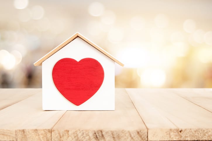 Small house on a wooden floor with a big red heart in the center.
