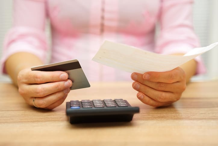 woman is holding bill and credit card in hands